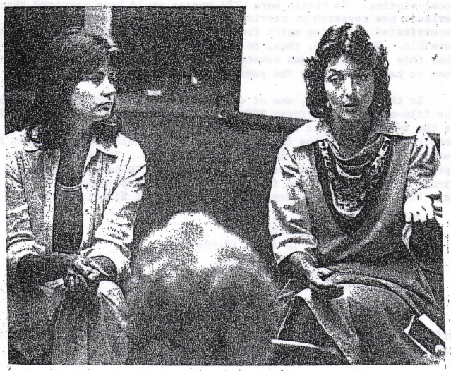 A black and white photo of two women talking to an audience.
